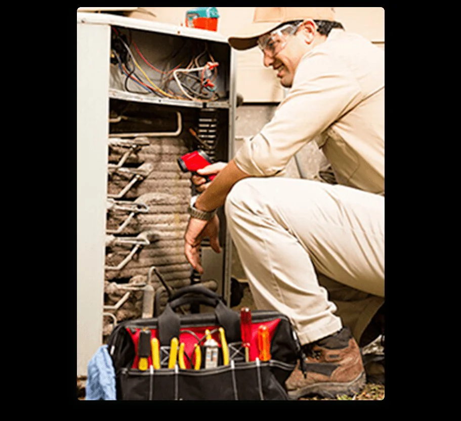 A professional HVAC technician in safety gear inspects an open AC unit