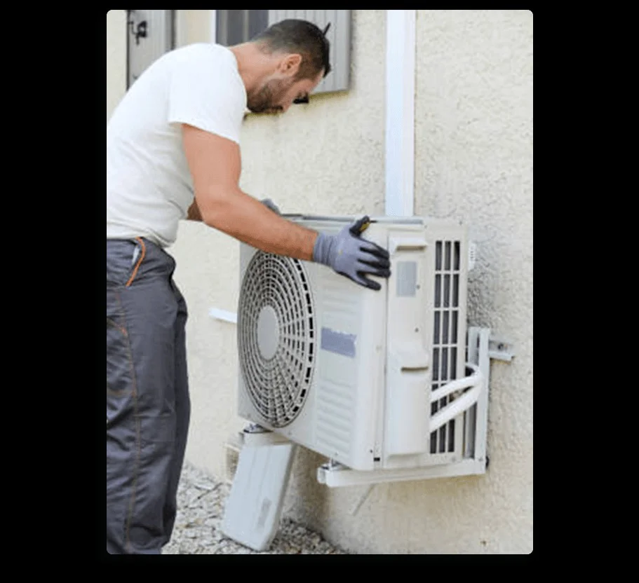 A technician in gloves carefully installs an outdoor air conditioning unit