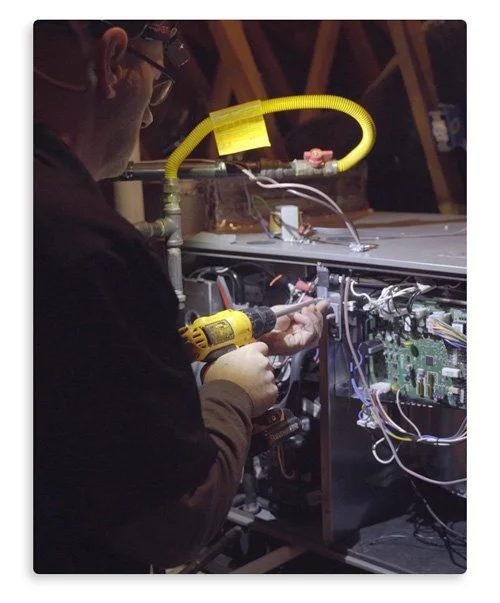 A technician uses a drill to service an energy-efficient heating system